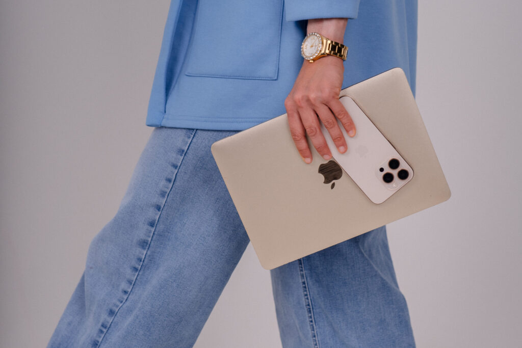 Die Unternehmerin geht mit ihrem Laptop und Handy.